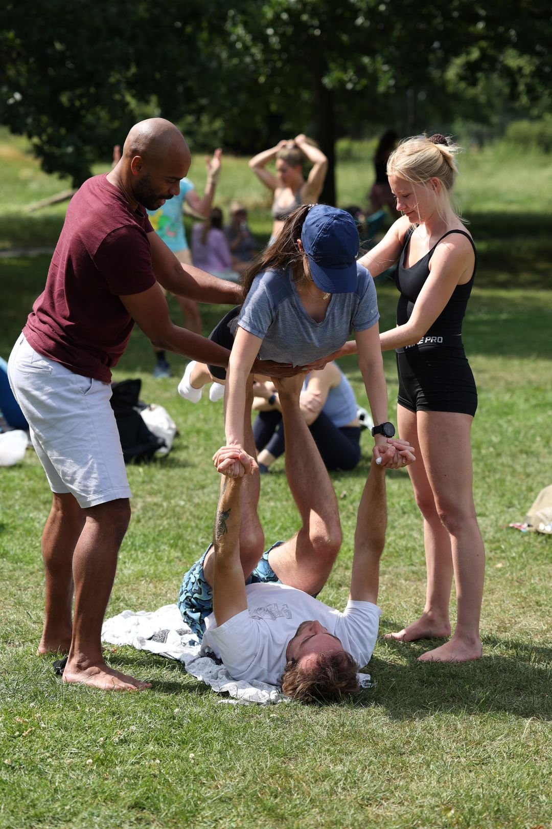 two acroyoga teachers spotting a two beginners in acro bird pose